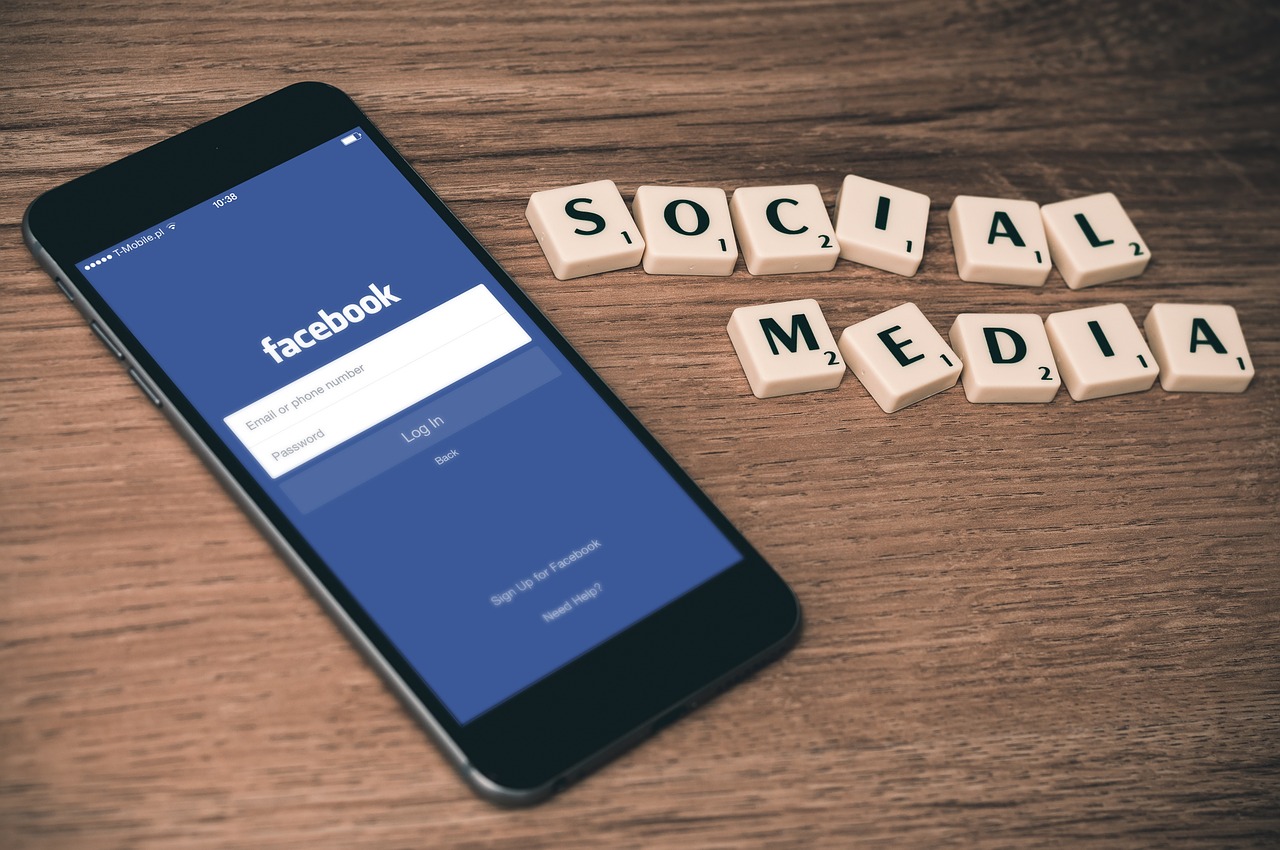 Social Media written with scrabble tiles next to a phone on the Facebook app. (International Social Media Marketing)