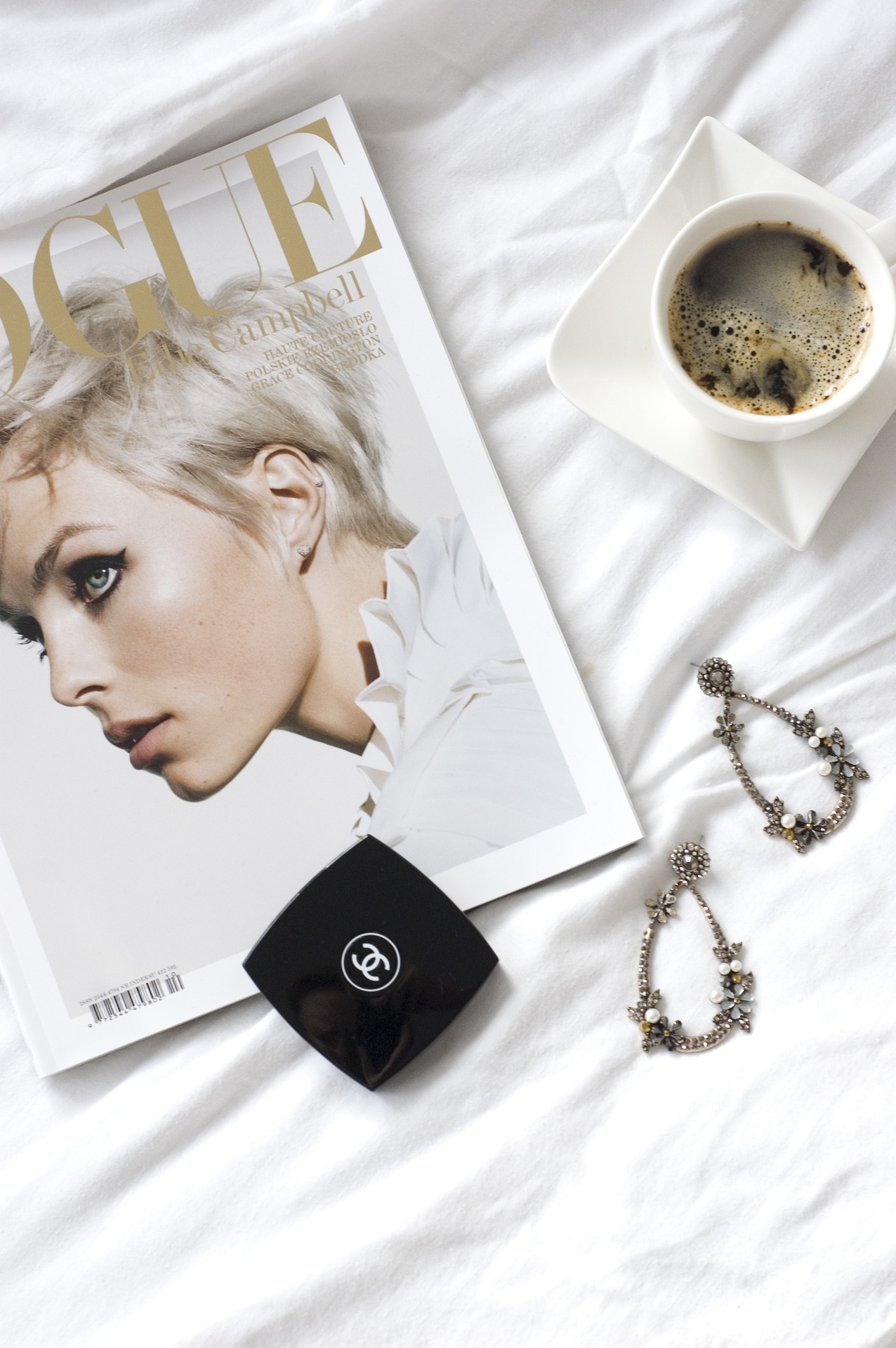 Still life featuring copy of Vogue magazine with accessories and a cup coffee